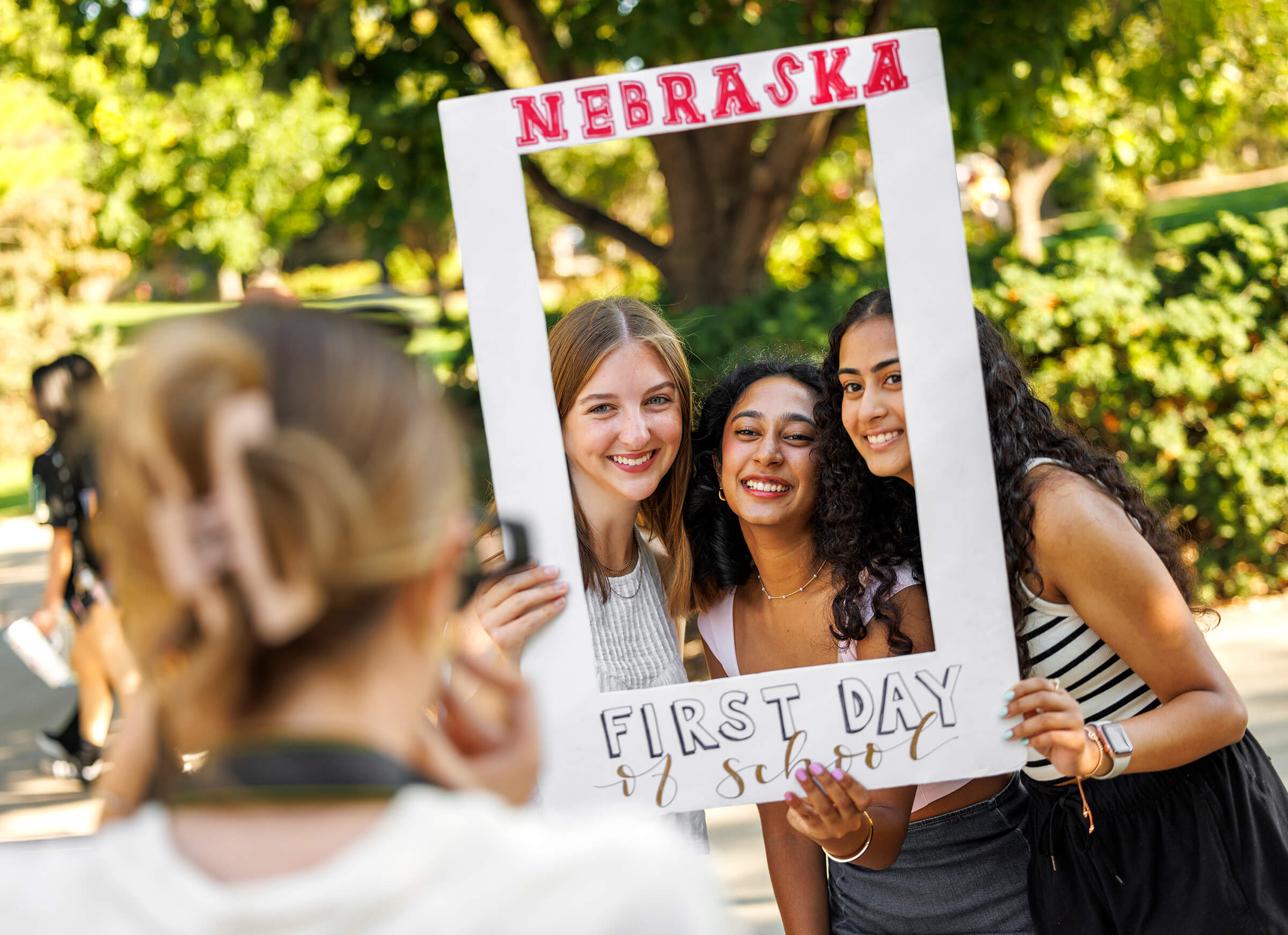 Three students holding up picture frame for portrait on first day of classes