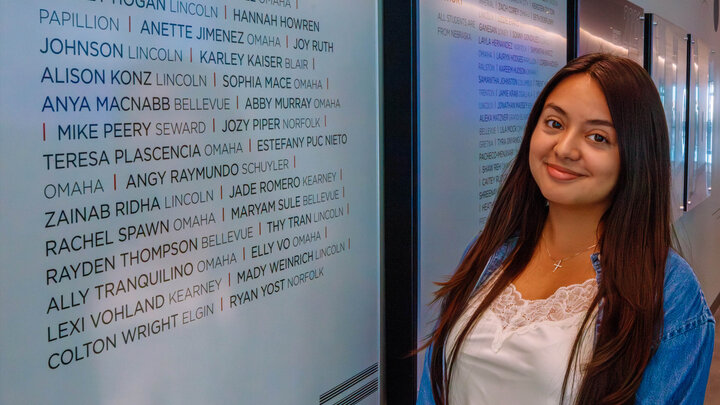 Student standing in front of mural in building