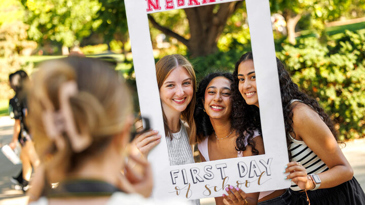 Three students holding up picture frame for portrait on first day of classes