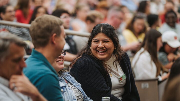 University staff member sitting in auditorium and talking