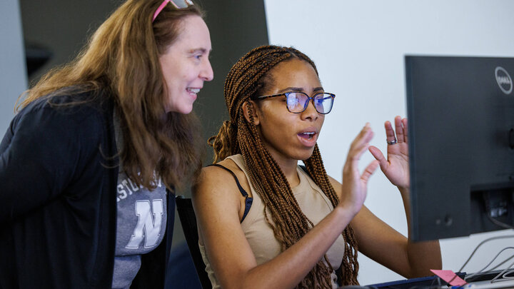 Student and faculty member reacting to something on computer screen