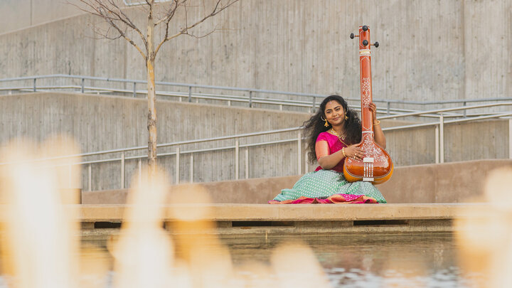 Student sitting by fountain with sitar