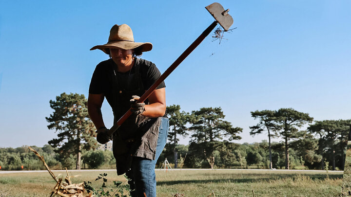 Student using a hoe to move earth in a field