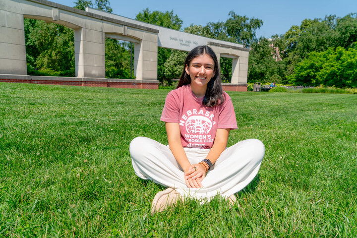 Student sitting cross-legged in grass in Coryele Common Area