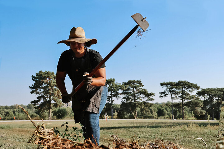 Student using a hoe to move earth in a field