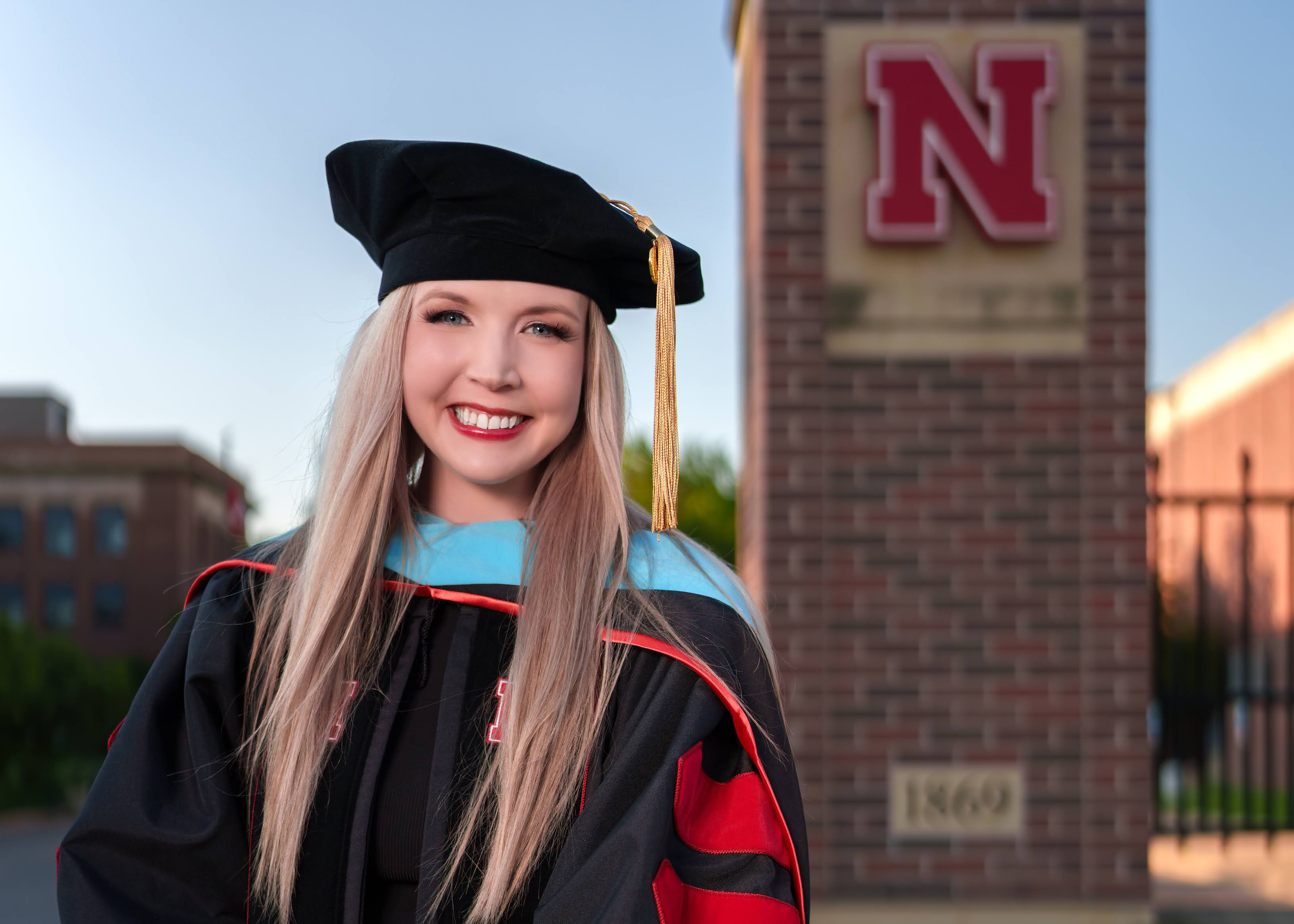 Dr. Amy Barry in her regalia in front of the N gate