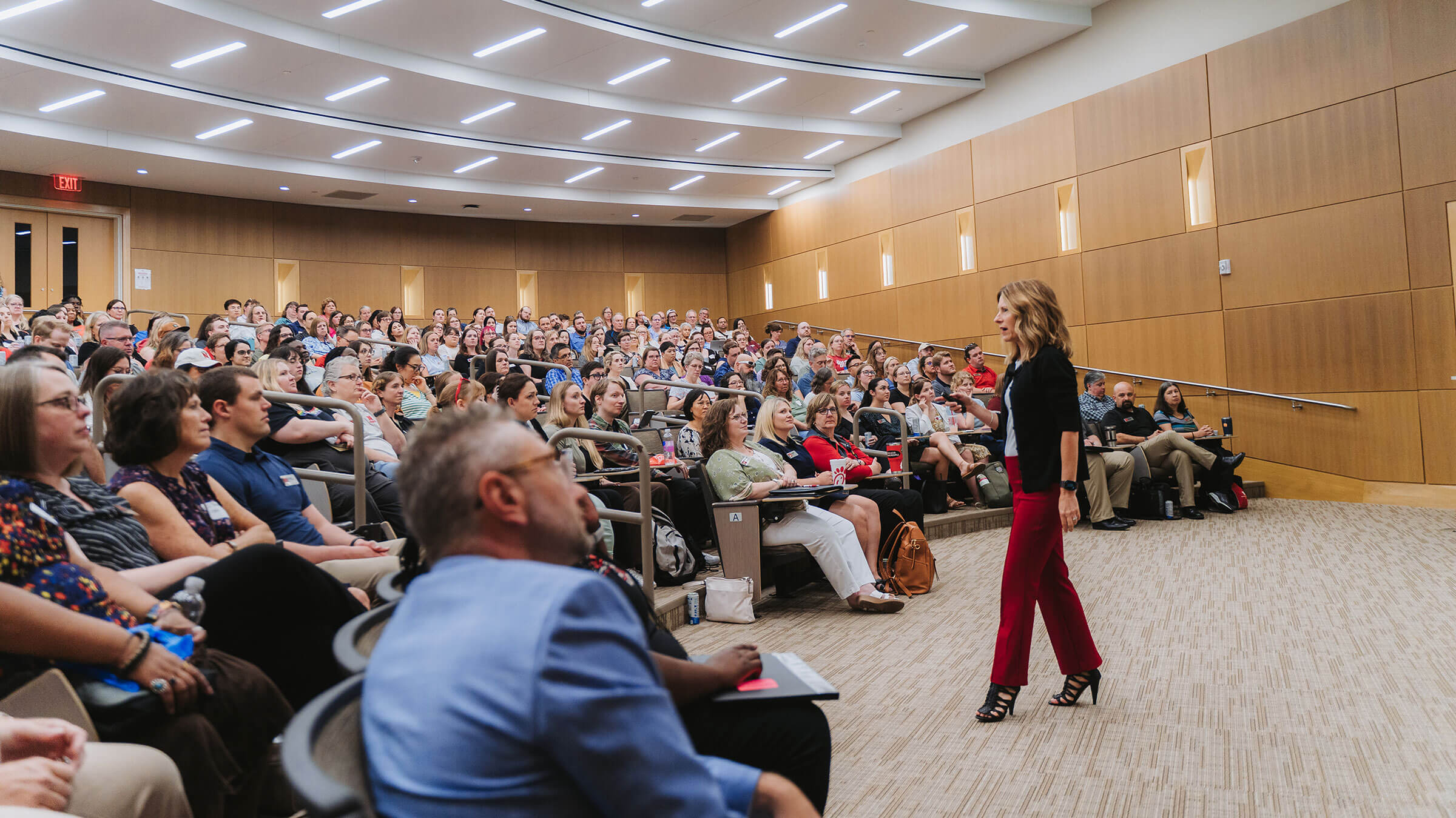 Staff member standing in front of auditorium audience and talking