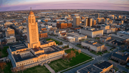 Downtown cityscape at sunset with a prominent government building and surrounding urban area.