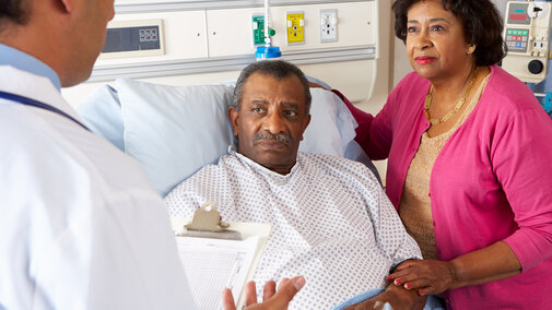 person in hospital bed with spouse listening to doctor talk