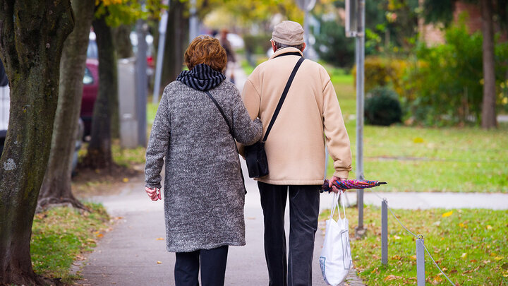 Man and woman walking on tree-lined sidewalk