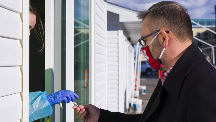 Chancellor Ronnie Green hands his saliva vial to Kaitlin Cartwright at the collection site by East Memorial Stadium. Green was one of more than 4,000 Huskers who were tested on Jan. 19, the first day testing was offered to the entire campus community.