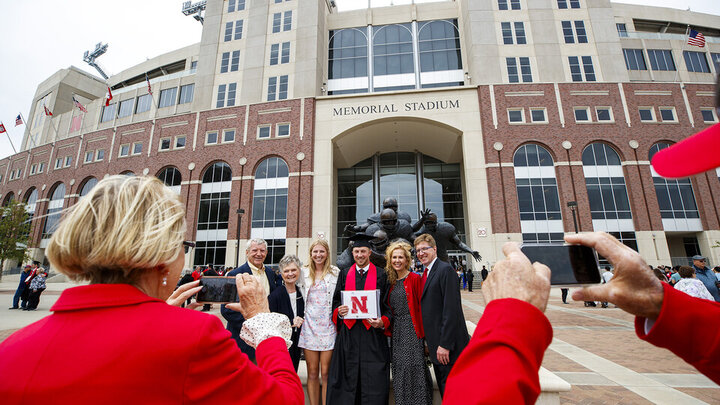 A family pauses outside the east side of Memorial Stadium to shoot graduate photos after the first commencement ceremony on May 8. The baggie of $200 in cash dropped on the south side of the stadium was found in the East Stadium parking lot by the family