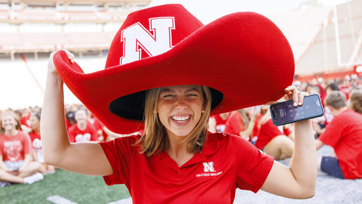 Claire Kelly, a New Student Enrollment leader, tries on Herbie’s hat after the Class of 2027 "N" photo in Memorial Stadium on Aug. 23.