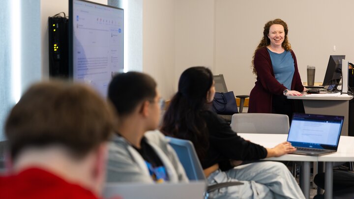 A woman stands in front of a classroom of students.