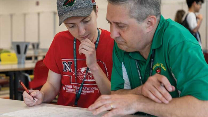A volunteer works with a student during a Science Olympiad.