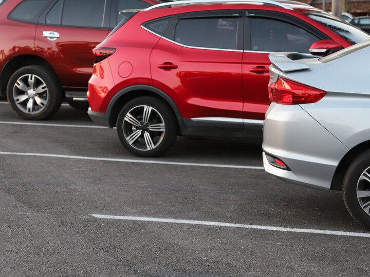 Cars parked in a row in an outdoor parking lot.