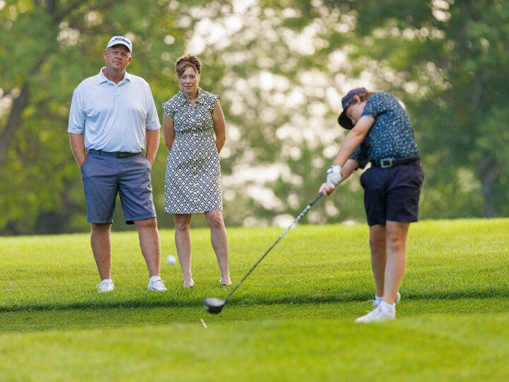 person playing golf with two people watching