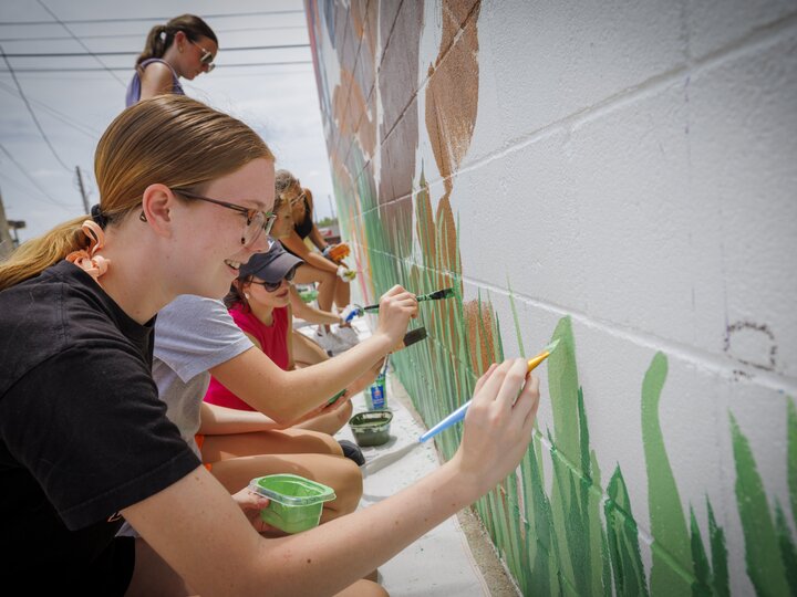 students painting a mural on a wall