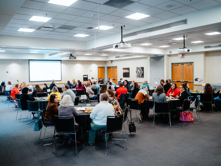 Group photo of staff at meeting tables in a large room