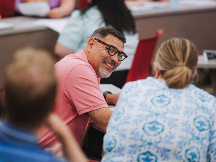 Over shoulder angle of two staff members having a discussion in a larger room