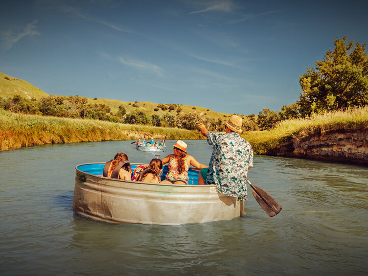 people floating in river in a cattle tank