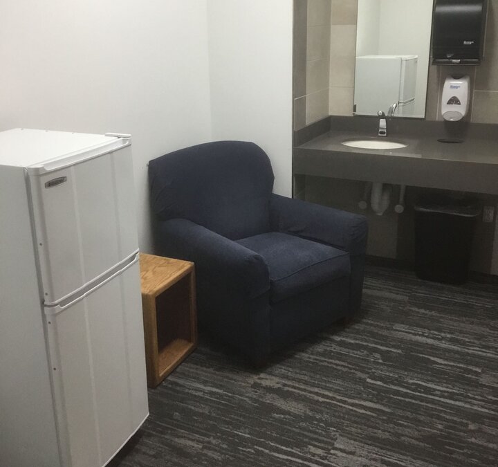 small fridge and chair in room with sink