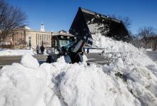 A Landscape Services worker uses a tractor to shift snow along R Street. On snowy days, the Landscape Services crew comes to campus early to clear sidewalks and building entrances.